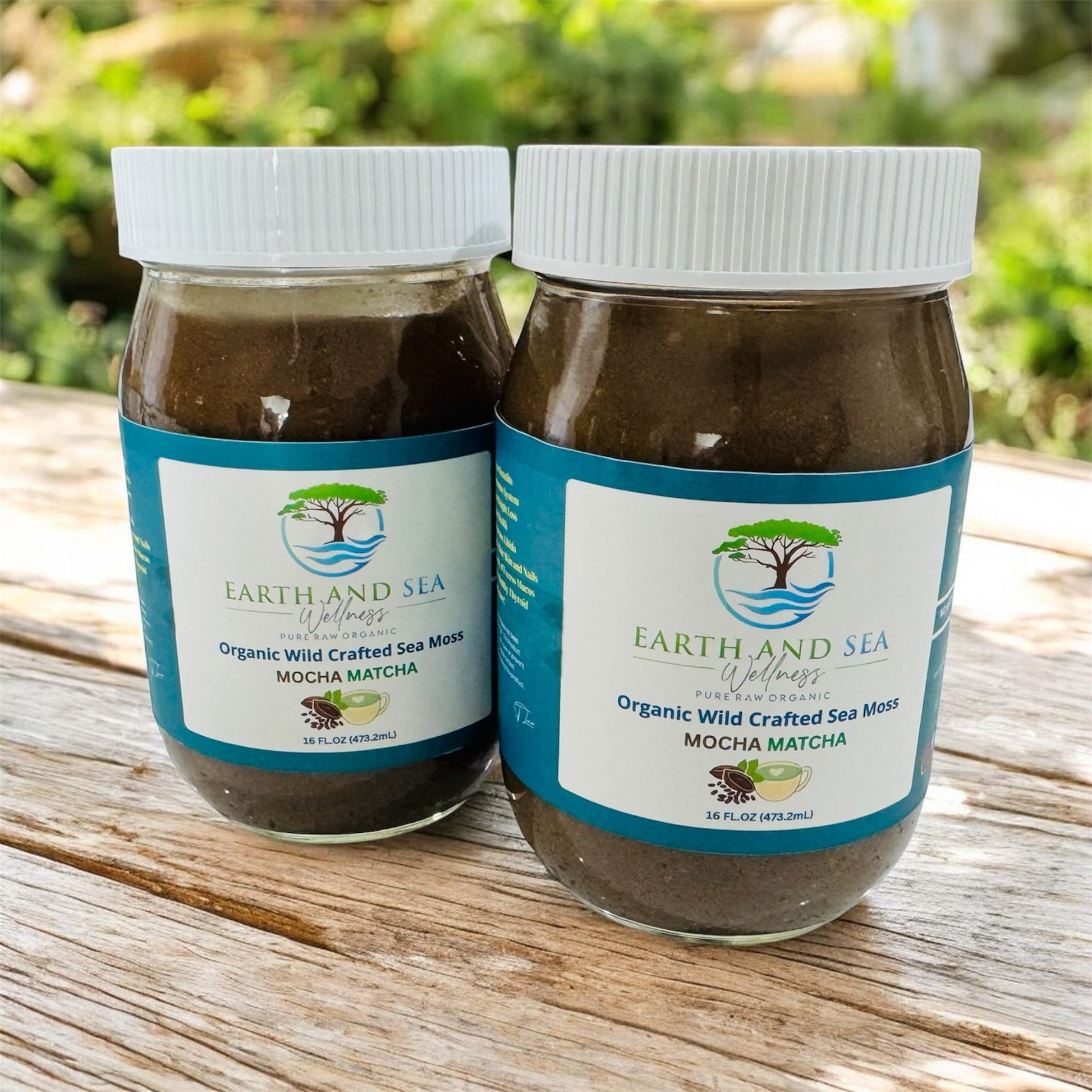 Two jars of Earth and Sea Wellness Organic Wild Crafted Sea Moss Mocha Matcha on a wooden surface with a blurred green background.